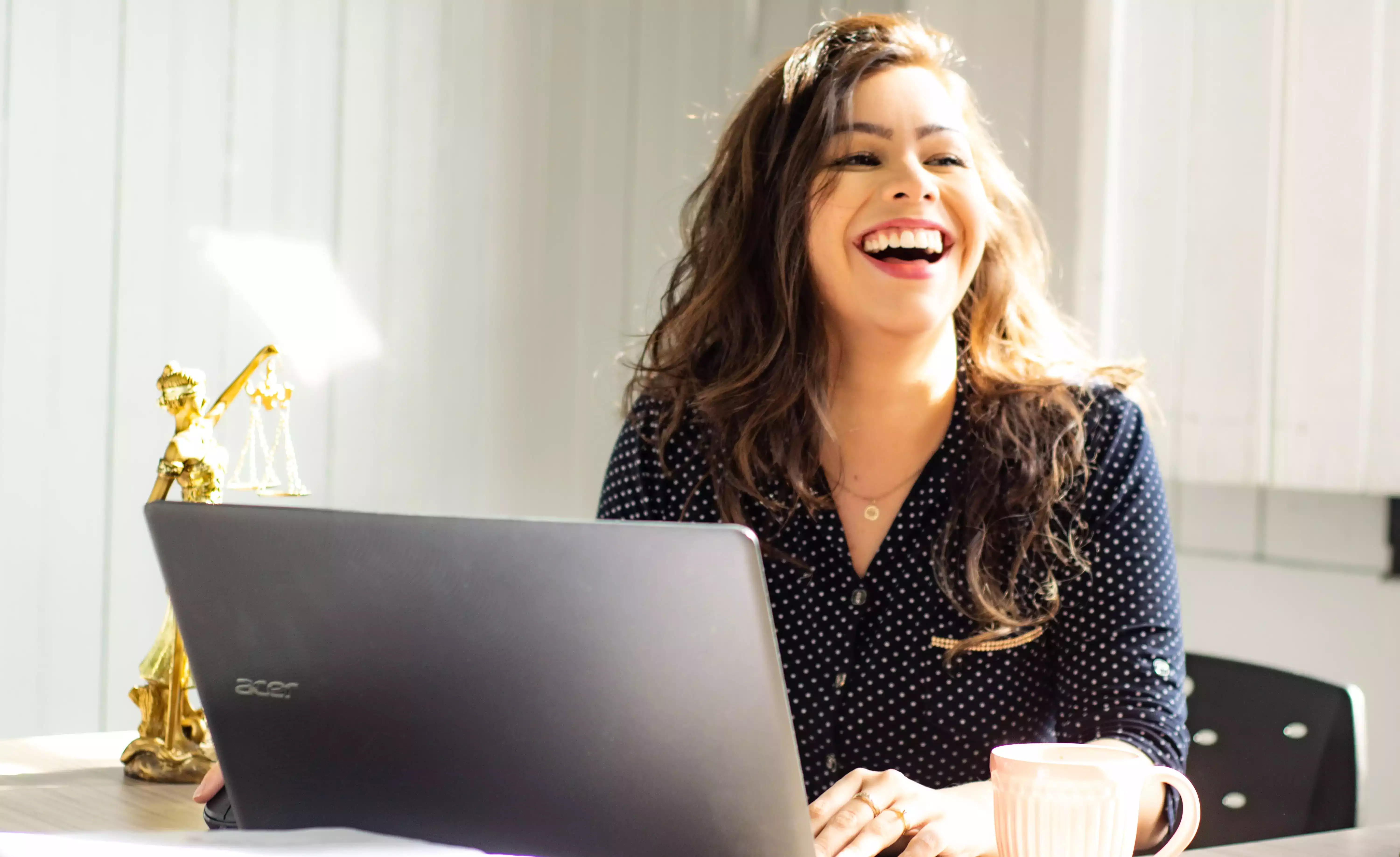 Photo d'une femme en entreprise derriere son ordinateur entrain de sourire